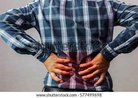 Men with low back pain on a gray background / medical and health concepts.
