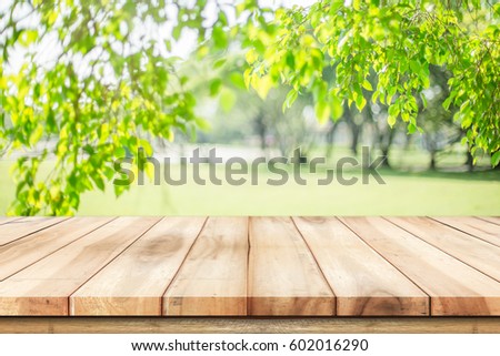 Empty wooden table with garden bokeh for a catering or food background with a country outdoor theme / Template mock up for display of product