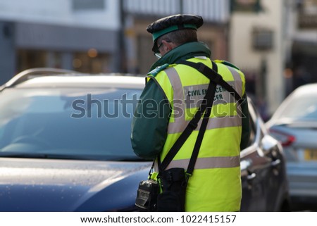 traffic warden civil enforcement officer wearing reflective yellow vest issuing fixed penalty parking ticket fine