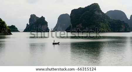 Lonely boat drifts through calm Halong Bay islands, Vietnam,Asia