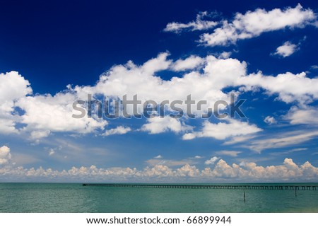 Deep blue sky over ocean pier stretching into turquoise sea