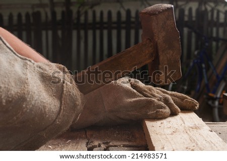 Carpenter knocking a nail into wood using hammer in his joinery