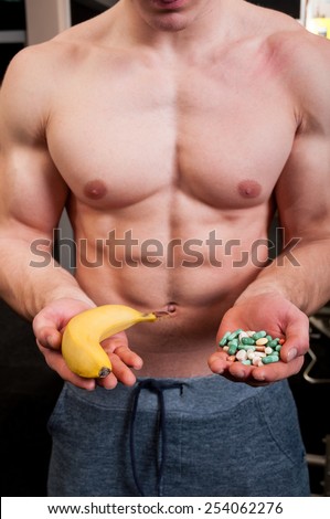 Muscle man choice between natural banana and a hand of pills