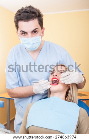 Young male dentist at work with a beautiful young blonde female patient