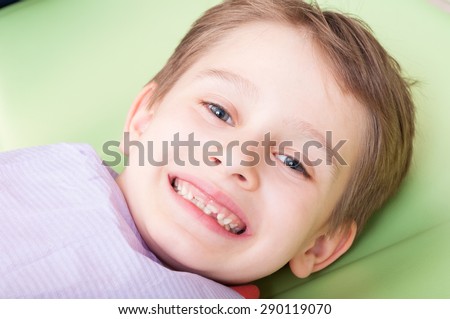 Smiling child with happy face on dentist chair or office. Kid with no fear of dentist concept