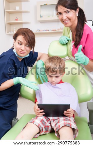 Modern dental team offering entertainment for kid patient as a wireless tablet with games