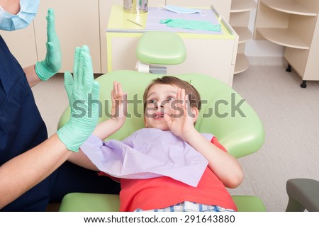 Woman doctor and kid patient playing clapping hands game in dentist office