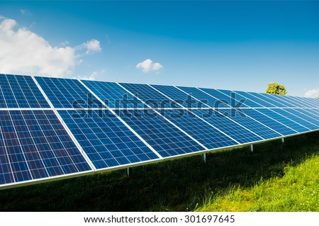 Solar power panels on green field with blue sky and copy space and text area