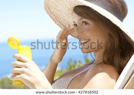 summer holidays and vacation - girl putting sun protection cream at the beach