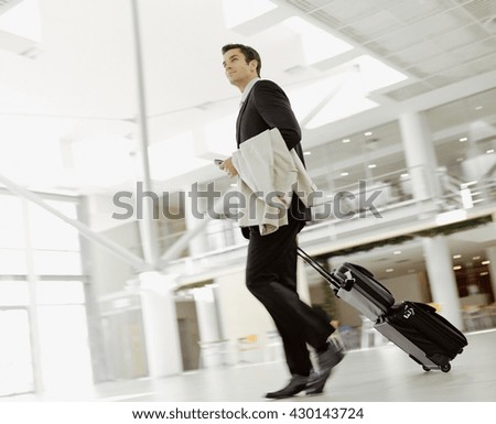 Young man pulling suitcase in modern airport terminal. Travelling guy concept