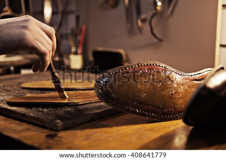 Shoemaker makes shoes for men.\
He smears special liquid  with a brush.