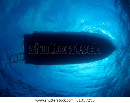 Dive Boat Silhouette Floating in Sunlit Blue Water Background