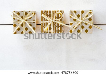 Holiday festive stylish fashionable golden gift packings packages boxes on a white wooden background