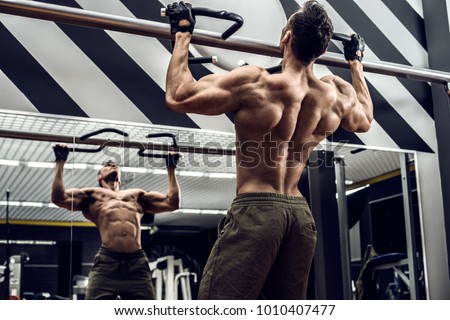 guy bodybuilder execute exercise pulling up on horizontal bar in gym, horizontal photo