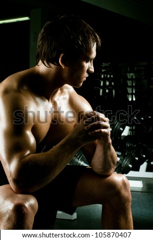 very power athletic guy rest  after execute exercise, in dark  sport-hall