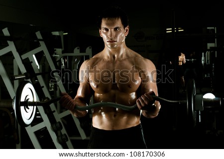 very power athletic guy ,  execute exercise with  weight, in  dark sport-hall