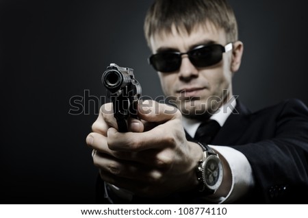 portrait  the  beautiful  man in black costume,  special-service agent or  body guard with  pistol