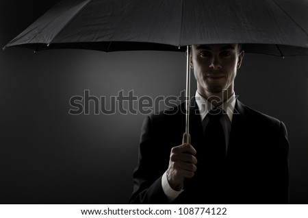 portrait  man the  beautiful  man in black costume with blak umbrella,  special-service agent or  body guard