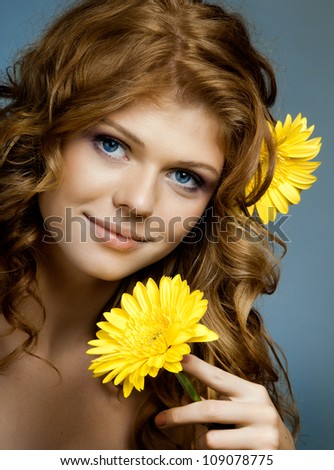 the very  pretty red-haired blue eyed young woman  with yellow flower,  smile , vertical close up portrait