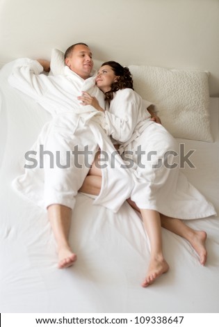 happy couple lie together in  bedstead on white bed,  morning wake up and embrace
