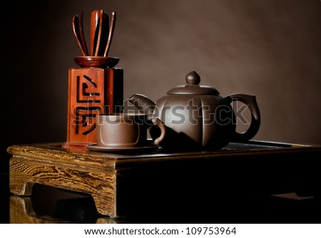 horizontal photo, still life of the clay teapot and  cup on brown background
