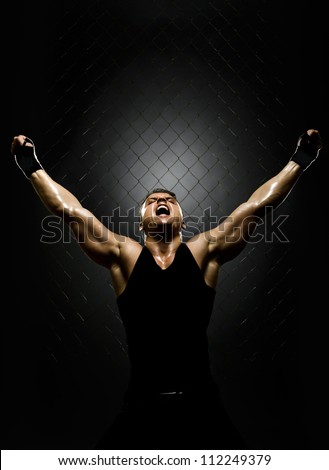 vertrical photo  muscular young  guy street-fighter,  triumphant cries  yell , hard light