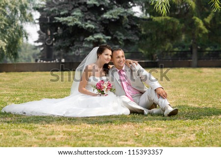 beautiful newly married couple  on nature in park , sit on  lawn and happy smile