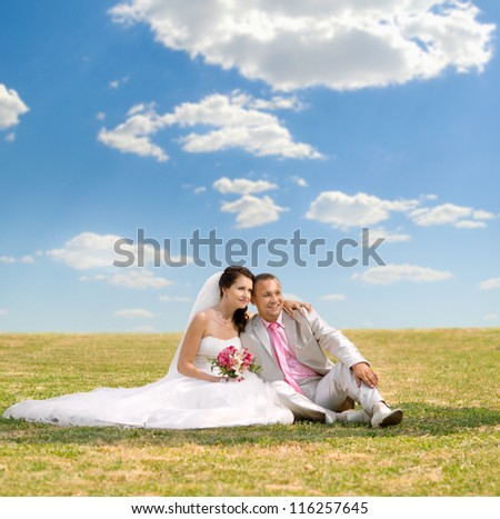 beautiful newly married couple  on nature in park , sit on  lawn and happy smile