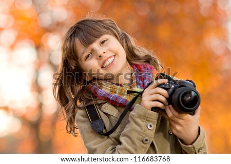 horizontal photo, happy beautiful little girl with photocamera, autumnal portrait