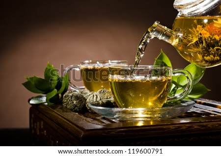 Horizontal Photo, Of The Glass Teapot Flow Green Tea In Cup On Brown Background, Tea Ceremony