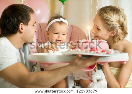 one-year-old little girl with daddy and mammy solemnize birthday, happy laughter, horizontal photo