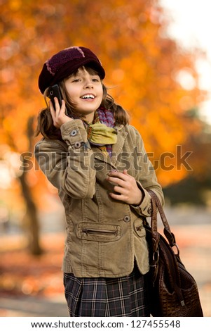 vertical photo,  stylish beautiful little girl hold  mobile phone and gladness talk