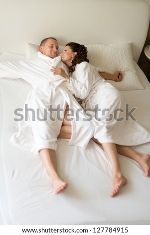 happy couple lie together in  bedstead on white bed,   sleep and embrace