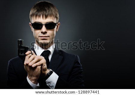 portrait the beautiful  man in black costume,  special-service agent or  body guard with  pistol