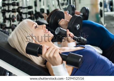 beautiful athletic girl ,  exercise with dumbbells and smile, in  sport-hall