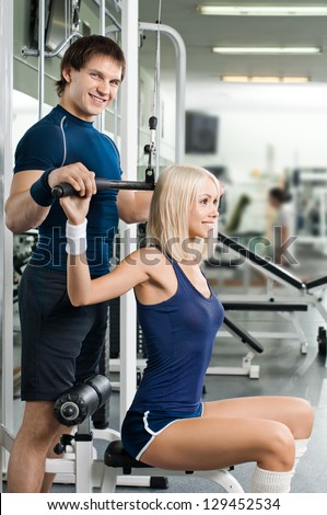 happy cutie athletic girl and guy,  execute exercise on sport-apparatus , in  sport-hall