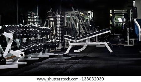 many black dumbbells in dark weight room, horizontal photo