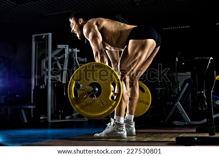 very brawny guy bodybuilder ,  execute exercise deadlift with weight, in gym