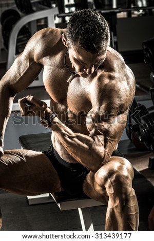 very power athletic guy ,  execute exercise with  dumbbells, on black background
