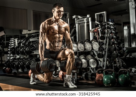 very power athletic guy ,  execute exercise with  dumbbells, in gym