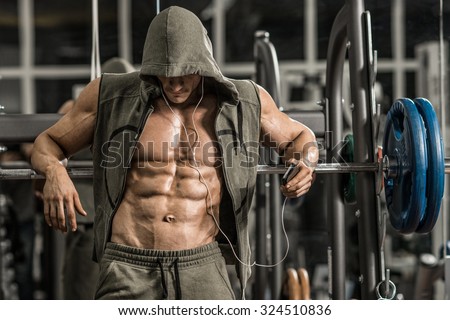 guy bodybuilder tired in gym and listen music with headset