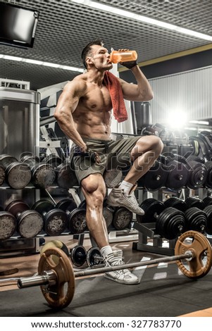 guy bodybuilder tired sit in gym and drink sportive nutrition - protein of shaker , vertical photo
