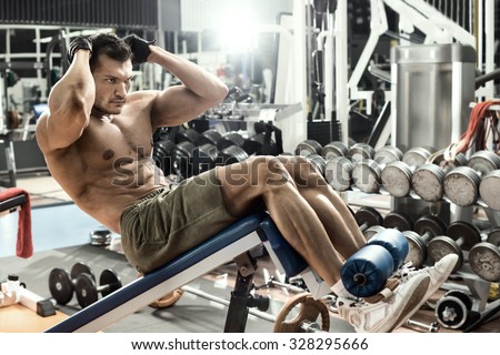 guy bodybuilder , execute exercise on prelum abdominale on bench in gym, horizontal photo