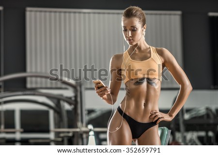 young fitness woman tired in gym and listen music with headset