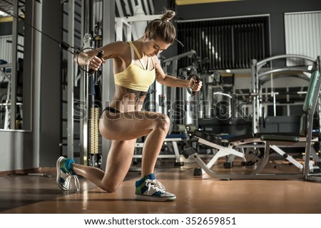 young fitness woman execute exercise with exercise-machine Cable Crossover in gym, horizontal photo