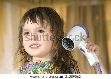 The cheerful beautiful Little girl dries hair smiles close up