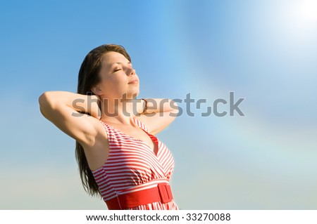 The young beautiful girl sunburn under a solar stream of light on a background of the sky