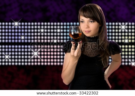 Young beautiful  the woman holds in one hand a glass with an alcoholic drink on black background