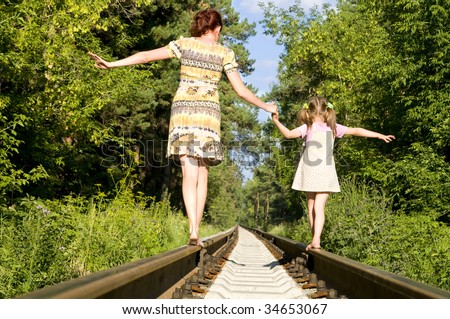 Mother with the daughter go on rails, a back to a camera, in a wood, in the summer, wood