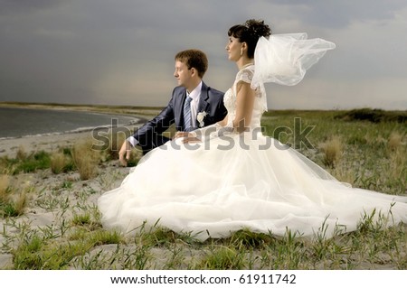 the beauty happy married  couple sit on coast, puff wind, imminent  storm-cloud